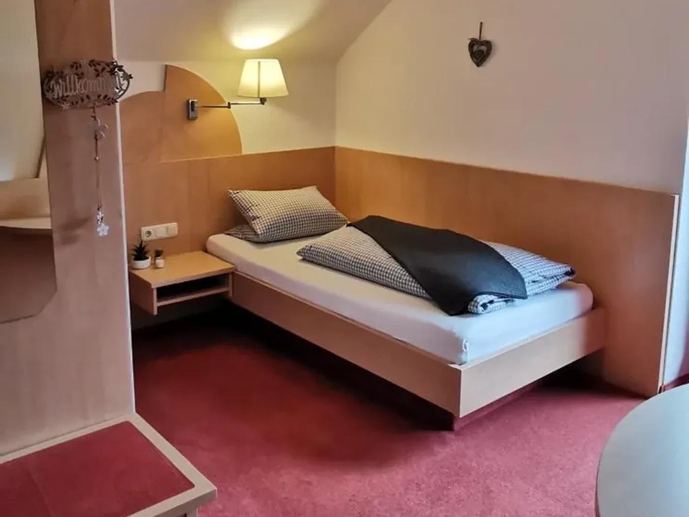 Einzelzimmer mit Bett, Schreibtisch und Dachfenster
